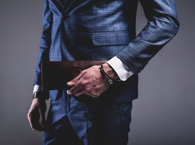 Foto gratuita retrato de moda de joven empresario guapo modelo hombre vestido con elegante traje azul sobre gris.