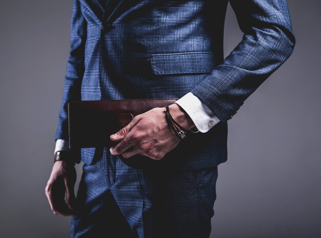 Retrato de moda de joven empresario guapo modelo hombre vestido con elegante traje azul sobre gris.