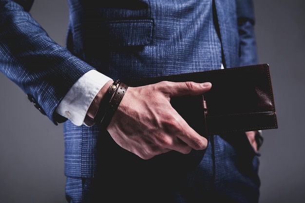 Foto gratuita retrato de moda de joven empresario guapo modelo hombre vestido con elegante traje azul sobre gris.