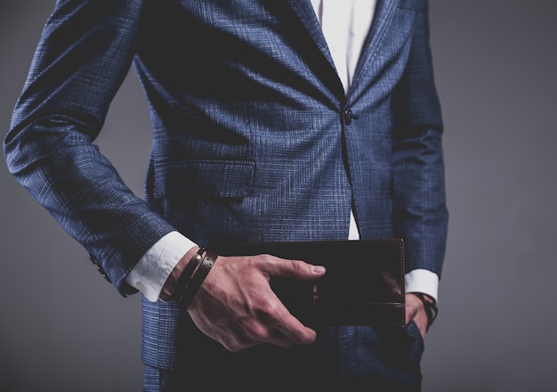 Retrato de moda de joven empresario guapo modelo hombre vestido con elegante traje azul sobre gris.