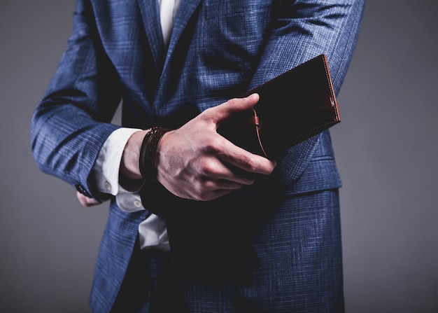 Retrato de moda de joven empresario guapo modelo hombre vestido con elegante traje azul sobre gris.