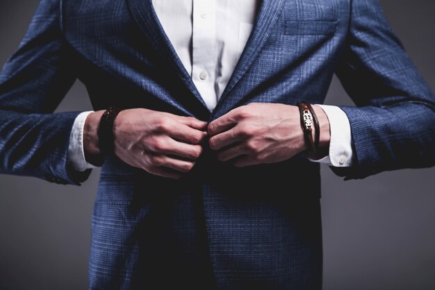 Retrato de moda de joven empresario guapo modelo hombre vestido con elegante traje azul sobre gris.