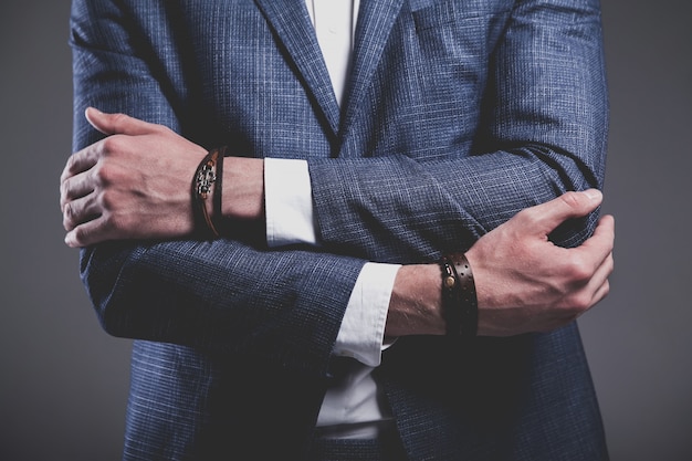 Retrato de moda de joven empresario guapo modelo hombre vestido con elegante traje azul sobre gris.