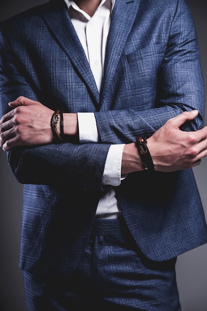 Retrato de moda de joven empresario guapo modelo hombre vestido con elegante traje azul sobre gris.