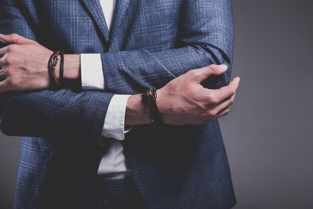 Retrato de moda de joven empresario guapo modelo hombre vestido con elegante traje azul sobre gris.