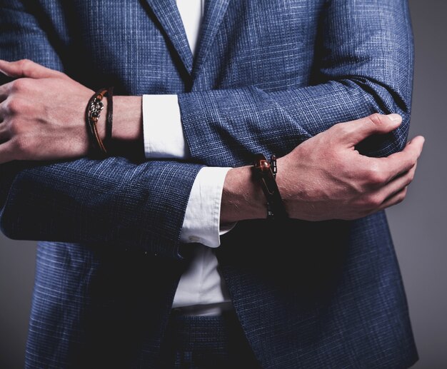 Retrato de moda de joven empresario guapo modelo hombre vestido con elegante traje azul sobre gris.