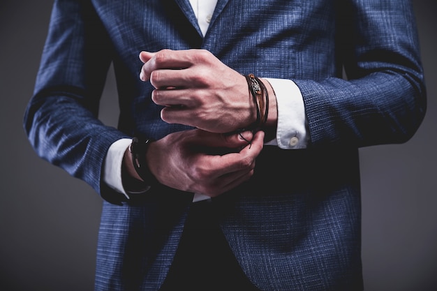 Retrato de moda de joven empresario guapo modelo hombre vestido con elegante traje azul sobre gris.