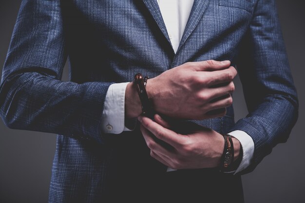 Retrato de moda de joven empresario guapo modelo hombre vestido con elegante traje azul sobre gris.