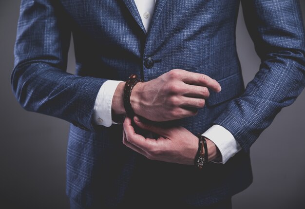 Retrato de moda de joven empresario guapo modelo hombre vestido con elegante traje azul sobre gris.