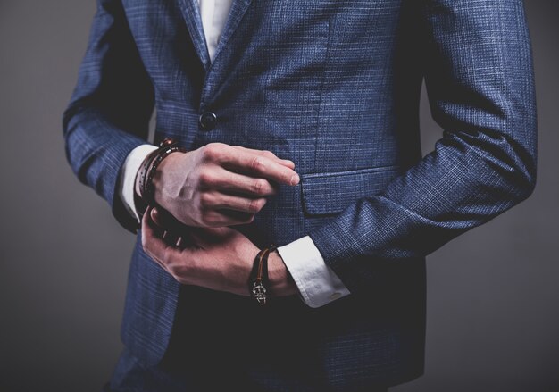 Retrato de moda de joven empresario guapo modelo hombre vestido con elegante traje azul sobre gris.