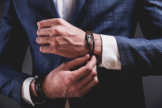 Retrato de moda de joven empresario guapo modelo hombre vestido con elegante traje azul sobre gris.