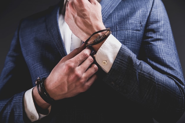 Retrato de moda de joven empresario guapo modelo hombre vestido con elegante traje azul sobre gris.