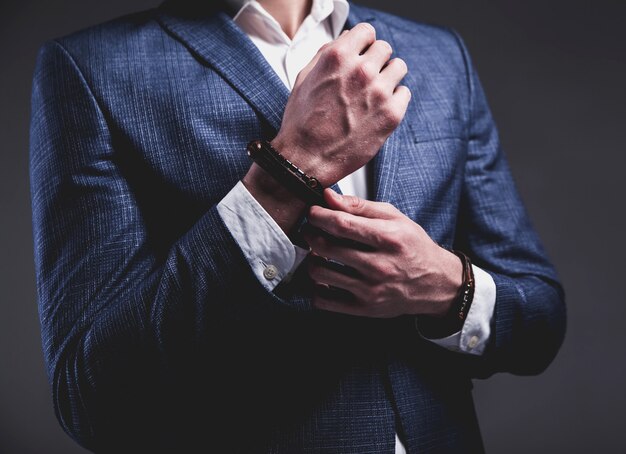 Retrato de moda de joven empresario guapo modelo hombre vestido con elegante traje azul sobre gris.