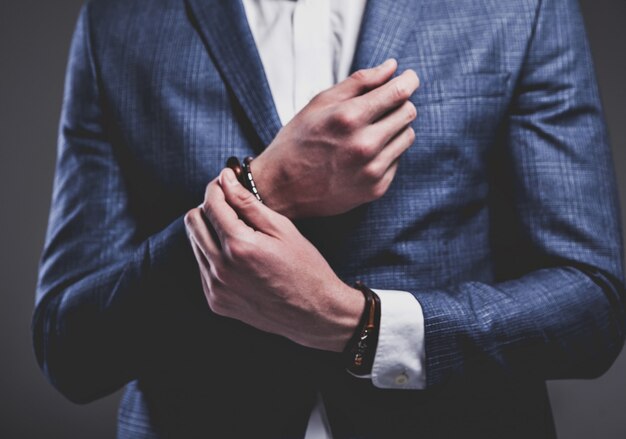 Retrato de moda de joven empresario guapo modelo hombre vestido con elegante traje azul sobre gris.