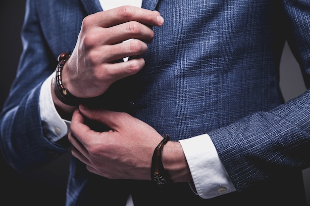 Retrato de moda de joven empresario guapo modelo hombre vestido con elegante traje azul sobre gris.