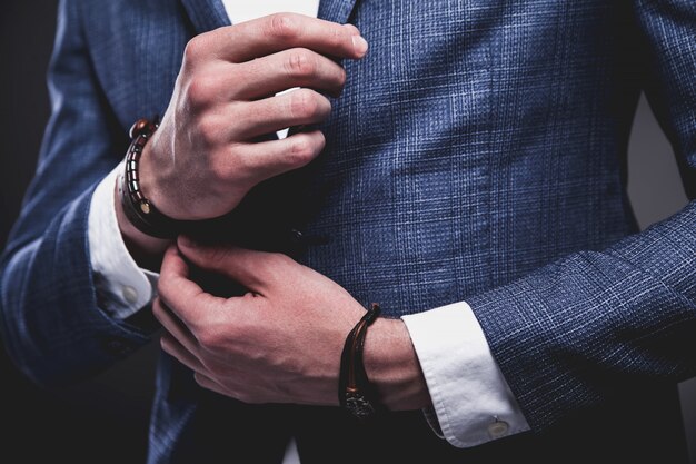 Retrato de moda de joven empresario guapo modelo hombre vestido con elegante traje azul sobre gris.