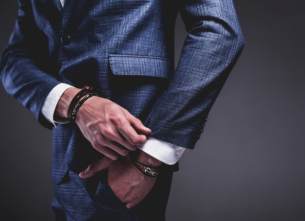 Retrato de moda de joven empresario guapo modelo hombre vestido con elegante traje azul sobre gris.