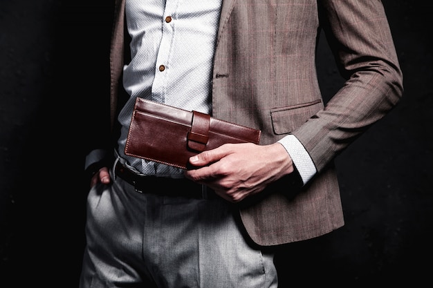 Retrato de moda de joven empresario guapo modelo hombre vestido con elegante traje marrón con accesorios