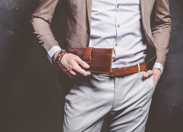 Retrato de moda de joven empresario guapo modelo hombre vestido con elegante traje marrón con accesorios