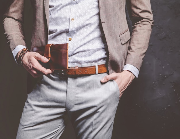 Retrato de moda de joven empresario guapo modelo hombre vestido con elegante traje marrón con accesorios