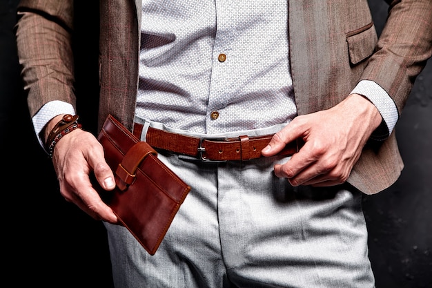 Retrato de moda de joven empresario guapo modelo hombre vestido con elegante traje marrón con accesorios