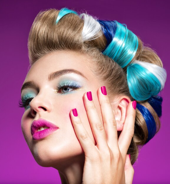 Retrato de moda de una mujer hermosa con maquillaje azul y uñas rosadas. Hermosa modelo de moda. Hermoso rostro de una chica atractiva - fondo rosa.