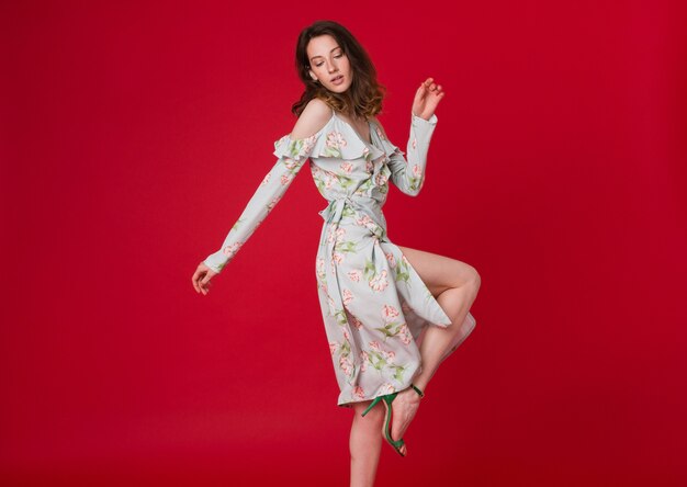 Retrato de moda de mujer joven y bonita en vestido estampado azul en estudio rojo