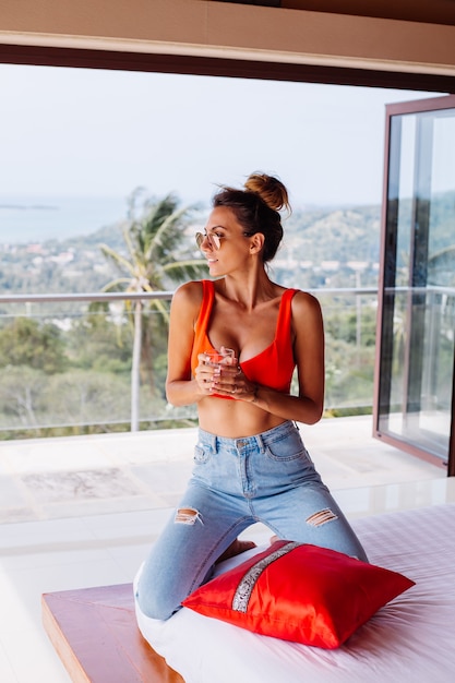 Retrato de moda de mujer joven en forma con abs en jeans y top rojo