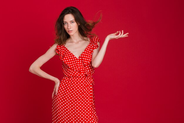 Retrato de moda de mujer joven sonriente en vestido rojo punteado en rojo