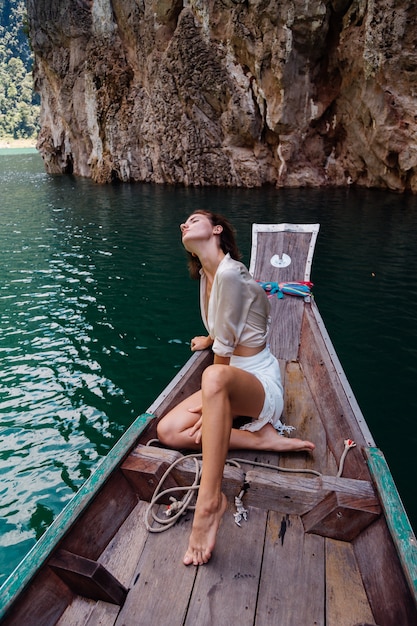 Retrato de moda de mujer joven de vacaciones, en barco de madera asiático