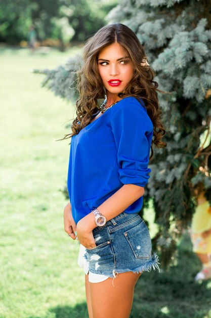 Retrato de moda de mujer morena impresionante en traje casual de verano Hermosa dama posando en el fondo verde del césped del parque de verano