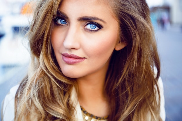 Retrato de moda de mujer sexy seductora con grandes ojos azules, labios carnosos, piel perfecta y peinado rizado largo y esponjoso de cerca. Maquillaje natural.
