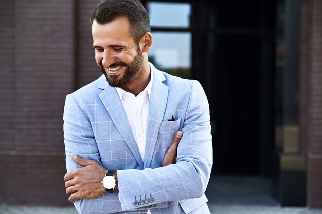 El retrato del modelo atractivo atractivo del hombre de negocios de moda se vistió en el traje azul elegante que presentaba en fondo de la calle. Metrosexual