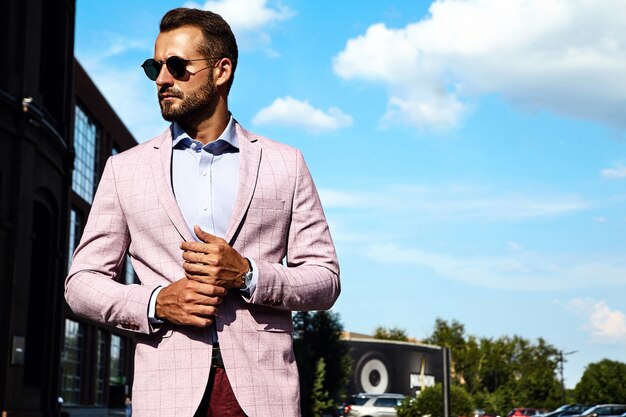 El retrato del modelo atractivo atractivo del hombre de negocios de la moda se vistió en el traje elegante que presentaba en fondo de la calle. Metrosexual