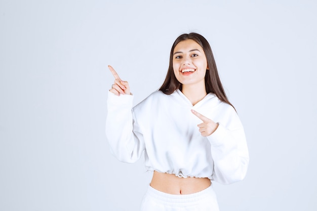 Retrato de modelo bastante joven posando y apuntando lejos.