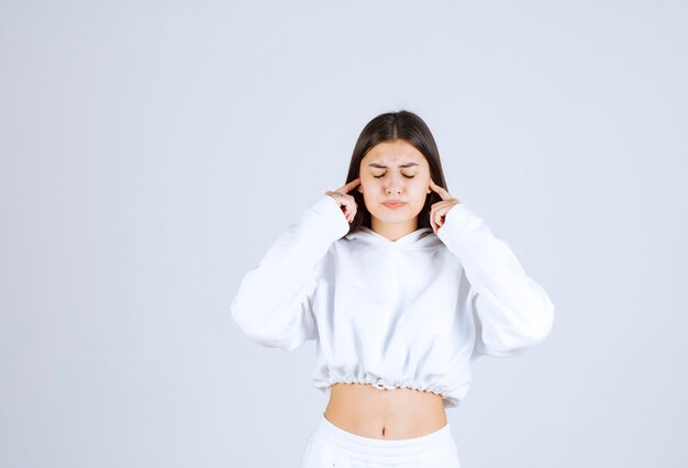 Retrato de un modelo bastante joven que cubre las orejas con los dedos índices.