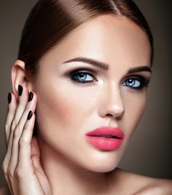 Retrato de modelo de chica hermosa con maquillaje de noche y peinado romántico tocando su piel. Labios rosados