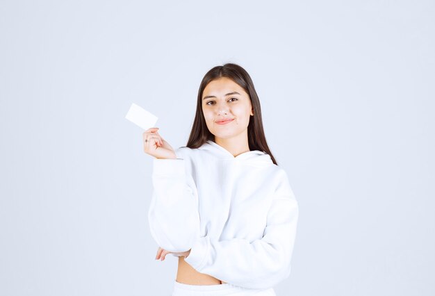 Retrato de un modelo de chica joven con una tarjeta sobre fondo blanco-gris.