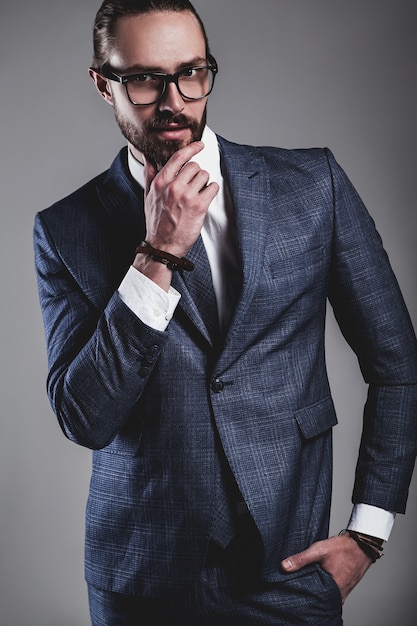 Retrato del modelo de empresario de moda guapo vestido con elegante traje azul con gafas