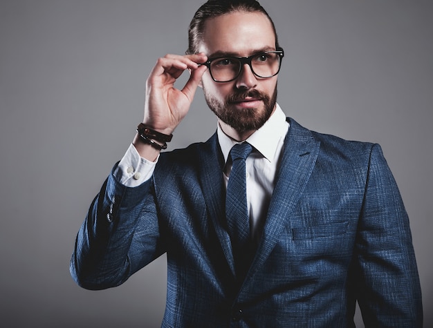 Retrato del modelo de empresario de moda guapo vestido con elegante traje azul con gafas