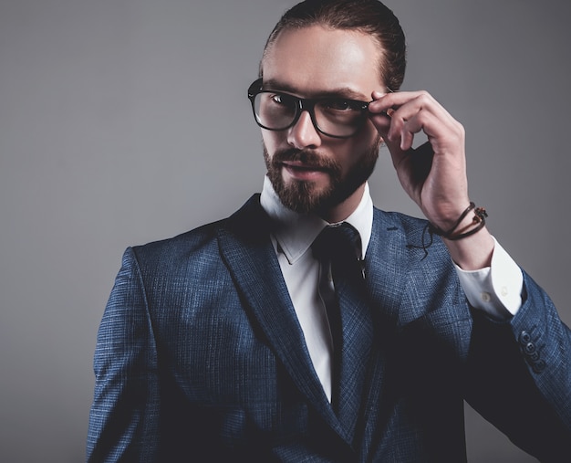 Retrato del modelo de empresario de moda guapo vestido con elegante traje azul con gafas