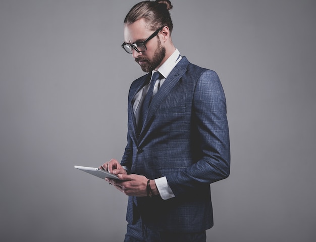 Retrato del modelo de empresario de moda guapo vestido con elegante traje azul con gafas