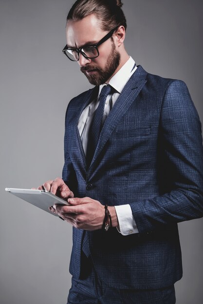Retrato del modelo de empresario de moda guapo vestido con elegante traje azul con gafas