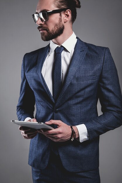 Retrato del modelo de empresario de moda guapo vestido con elegante traje azul con gafas