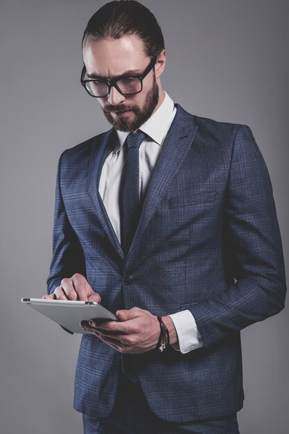 Retrato del modelo de empresario de moda guapo vestido con elegante traje azul con gafas