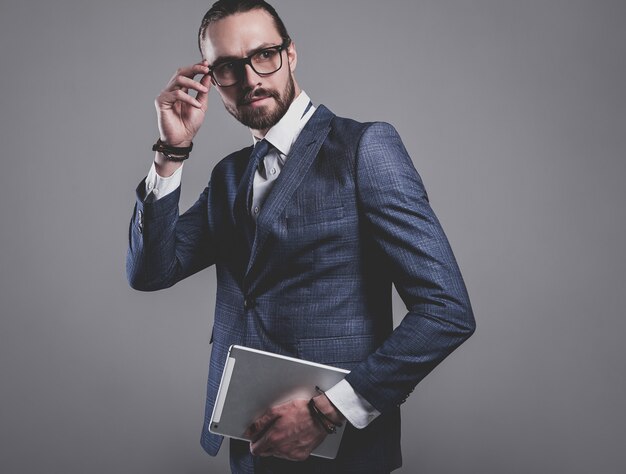 Retrato del modelo de empresario de moda guapo vestido con elegante traje azul con gafas