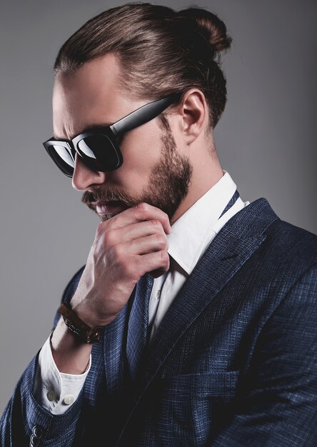 Retrato del modelo de empresario de moda guapo vestido con elegante traje azul con gafas