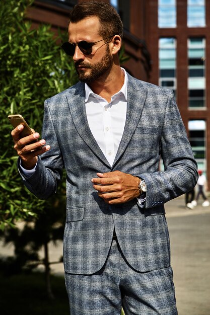 Retrato del modelo de empresario de moda guapo vestido con elegante traje a cuadros posando en la calle