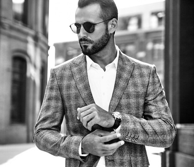 Retrato del modelo de empresario de moda guapo vestido con elegante traje a cuadros posando en la calle