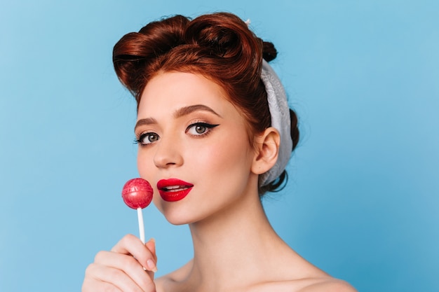 Foto gratuita retrato de modelo femenino curioso lamiendo piruleta. maravillosa mujer caucásica comiendo caramelos.